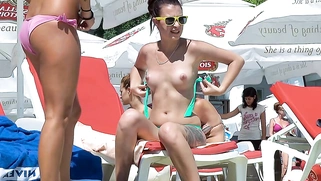 Nude beach teens sunbathes next to her man outdoors